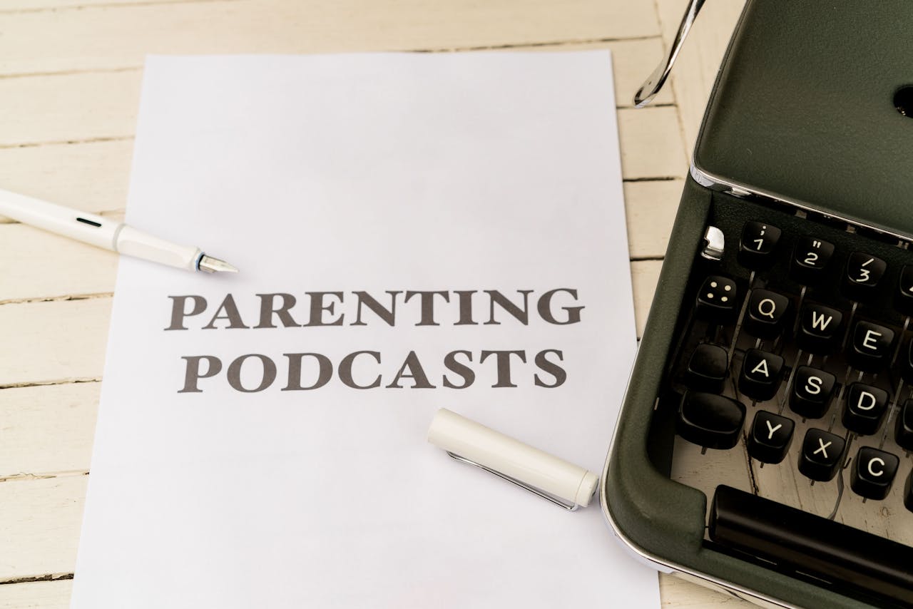 A vintage typewriter with a paper labeled Parenting Podcasts on a wooden desk.
